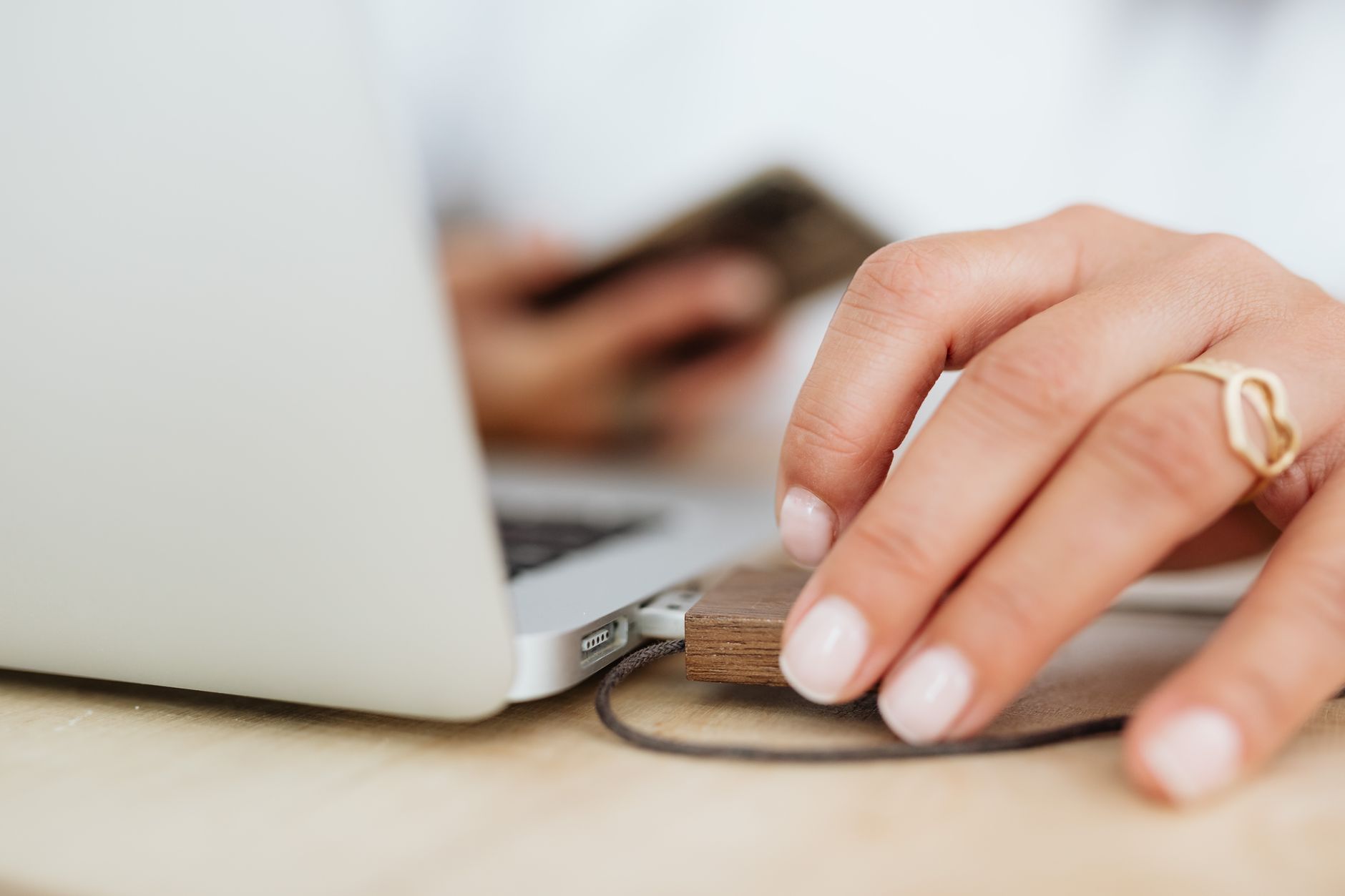 a person plugging an iPhone USB cable into a laptop while the phone screen shows a trust this computer prompt